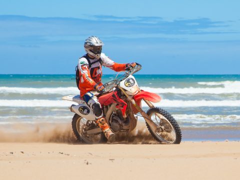 Moto rouge qui roulant a côté de la mer